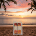 Maui Sunrise Wax Melt 2.5 Oz clamshell displayed on a tropical beach at sunset, ideal for home fragrance lovers seeking a soy-based scent.